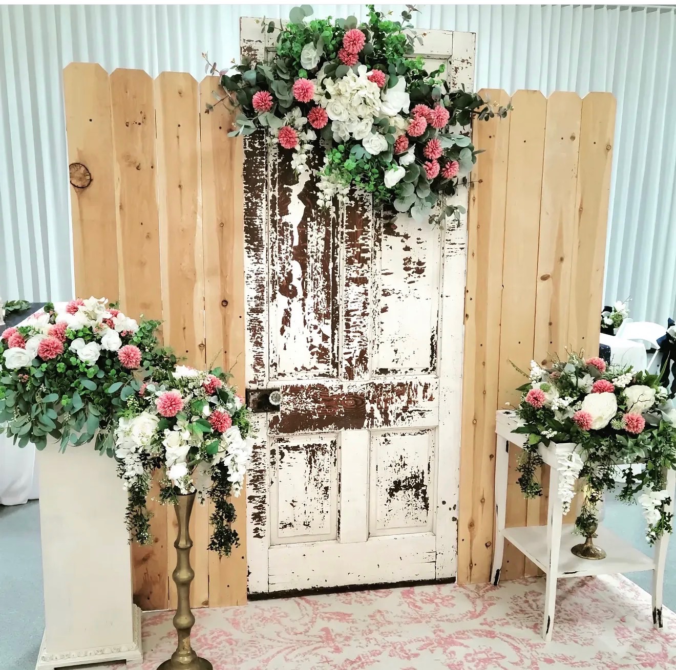 Rustic vintage door backdrop with lush eucalyptus and pink and white floral arrangements