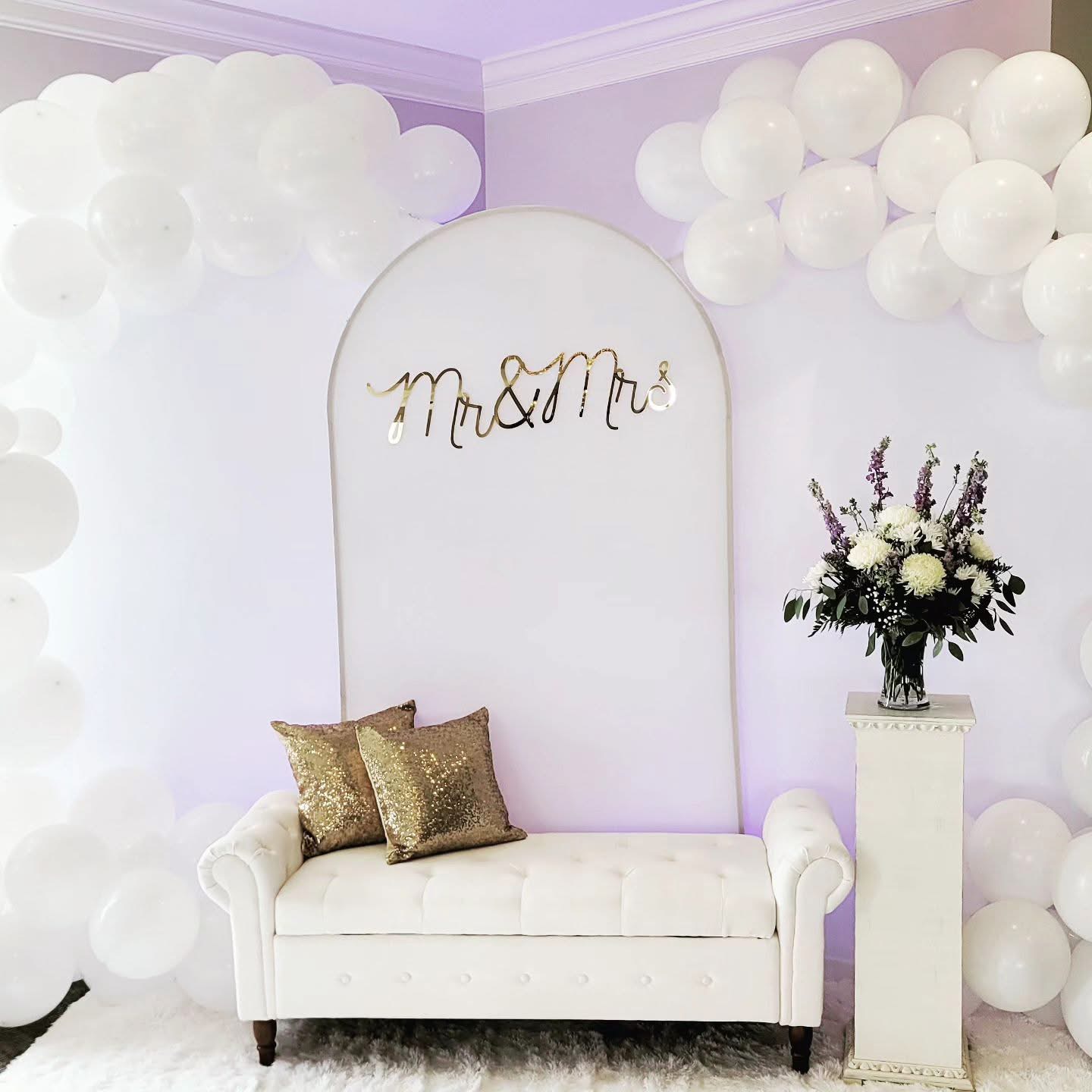 White Mr & Mrs arch backdrop with balloon garland, gold sequin pillows, and floral arrangement